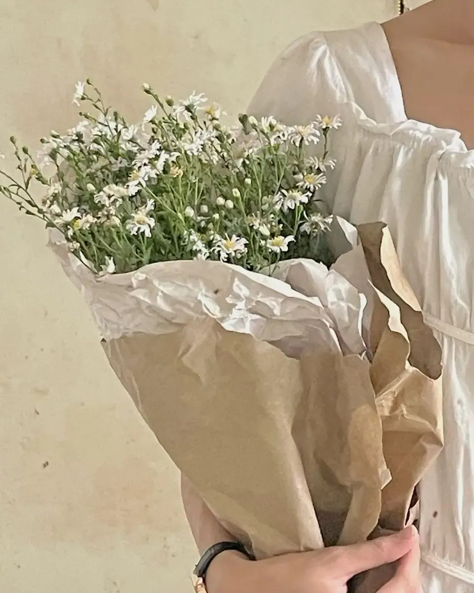 Hoa cúc họa mi nhỏ màu trắng gói giấy kraft, người cầm mặc váy trắng