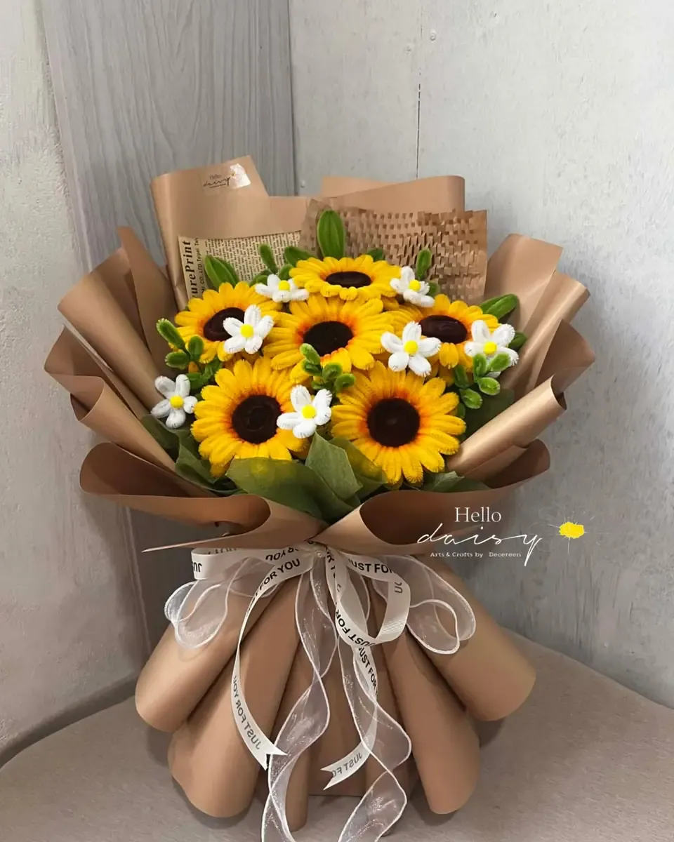 Bó hướng dương nhỏ cùng hoa trắng gói giấy kraft, buộc ruy băng trắng đặt trên ghế