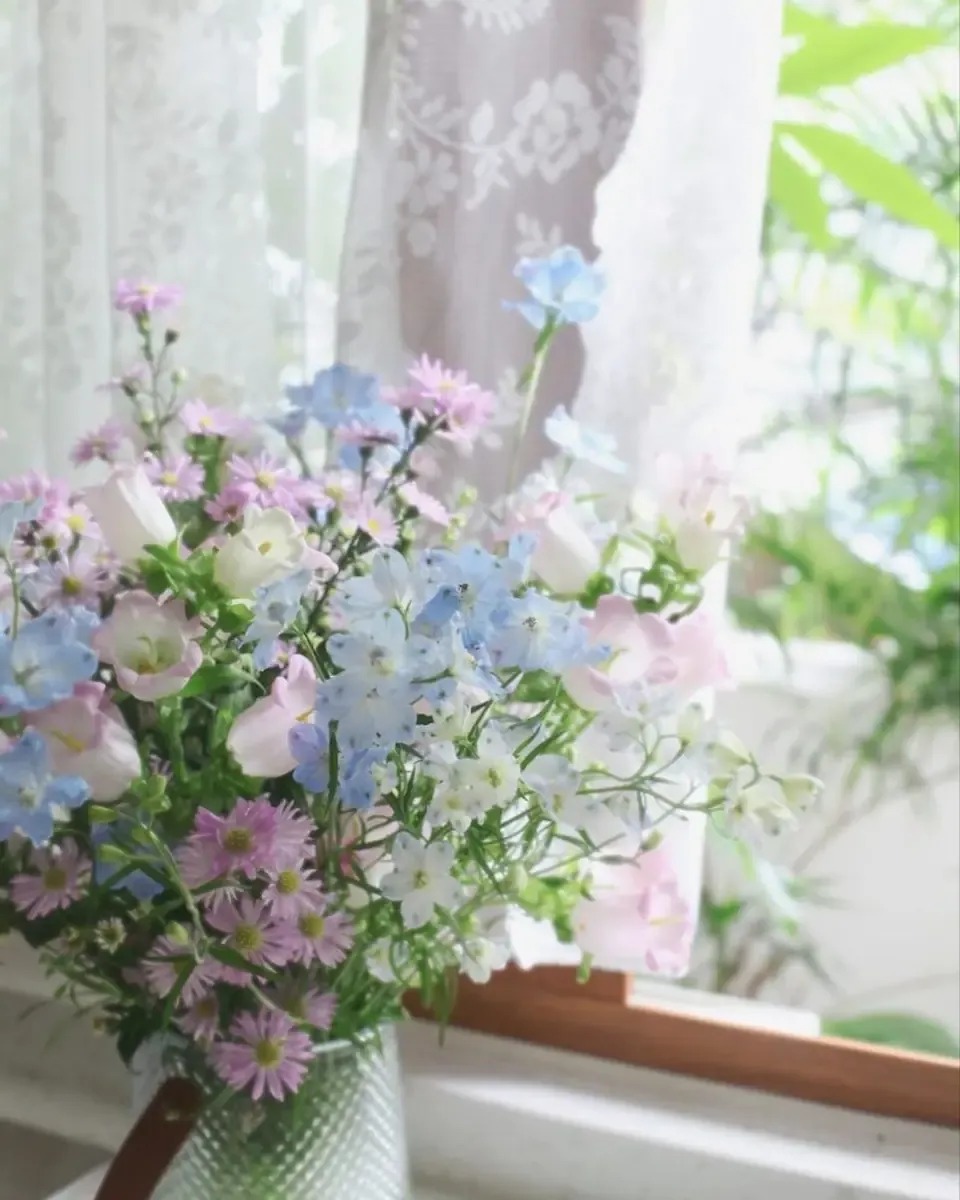 Hoa alstroemeria sắc hồng tím cắm trong bình thủy tinh bên cửa sổ có rèm ren