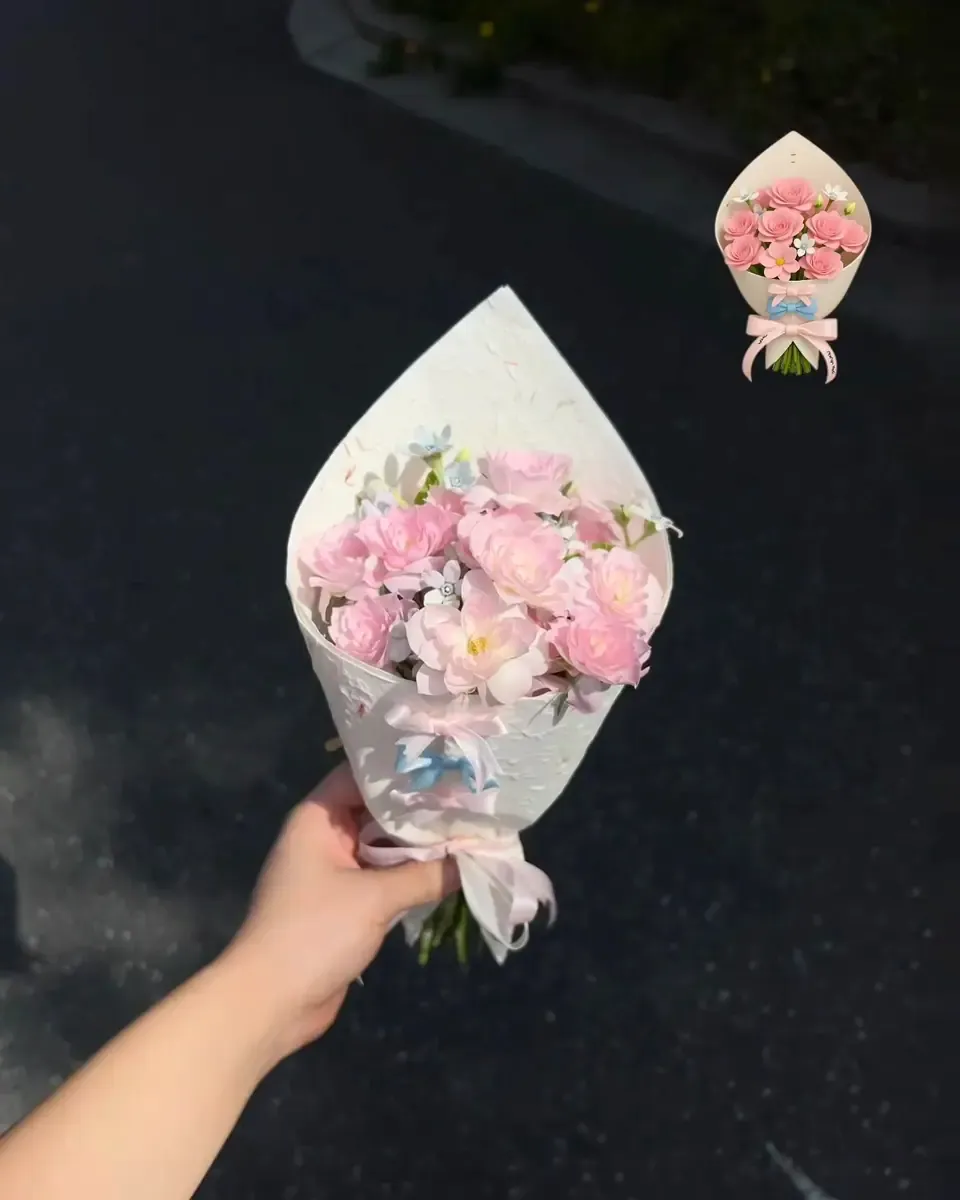 Bó hoa nhỏ màu hồng nhạt gói giấy hình nón trắng, được cầm trên tay