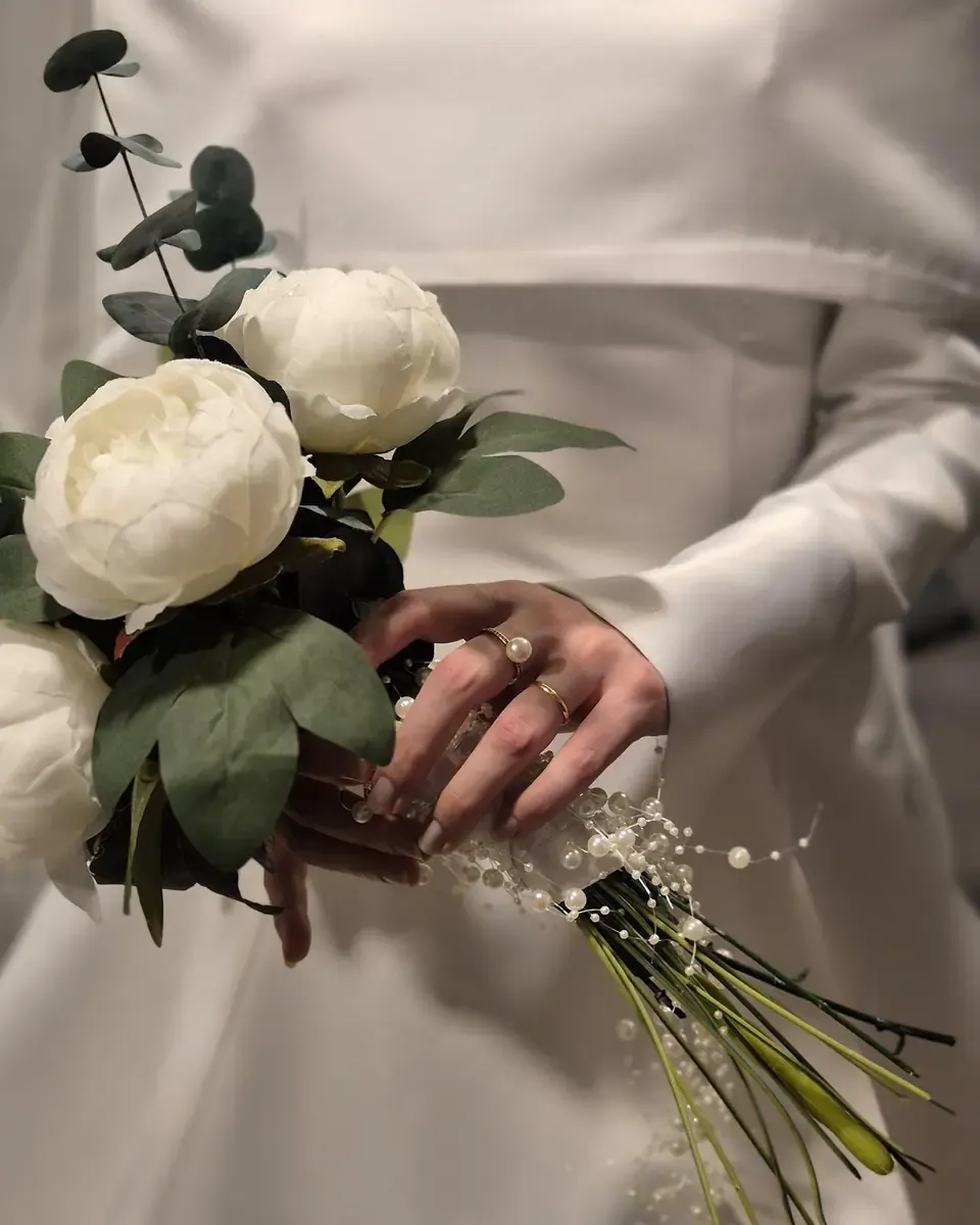 Bó hoa hồng trắng nhiều bông cầm trước váy satin xòe nhẹ của cô dâu