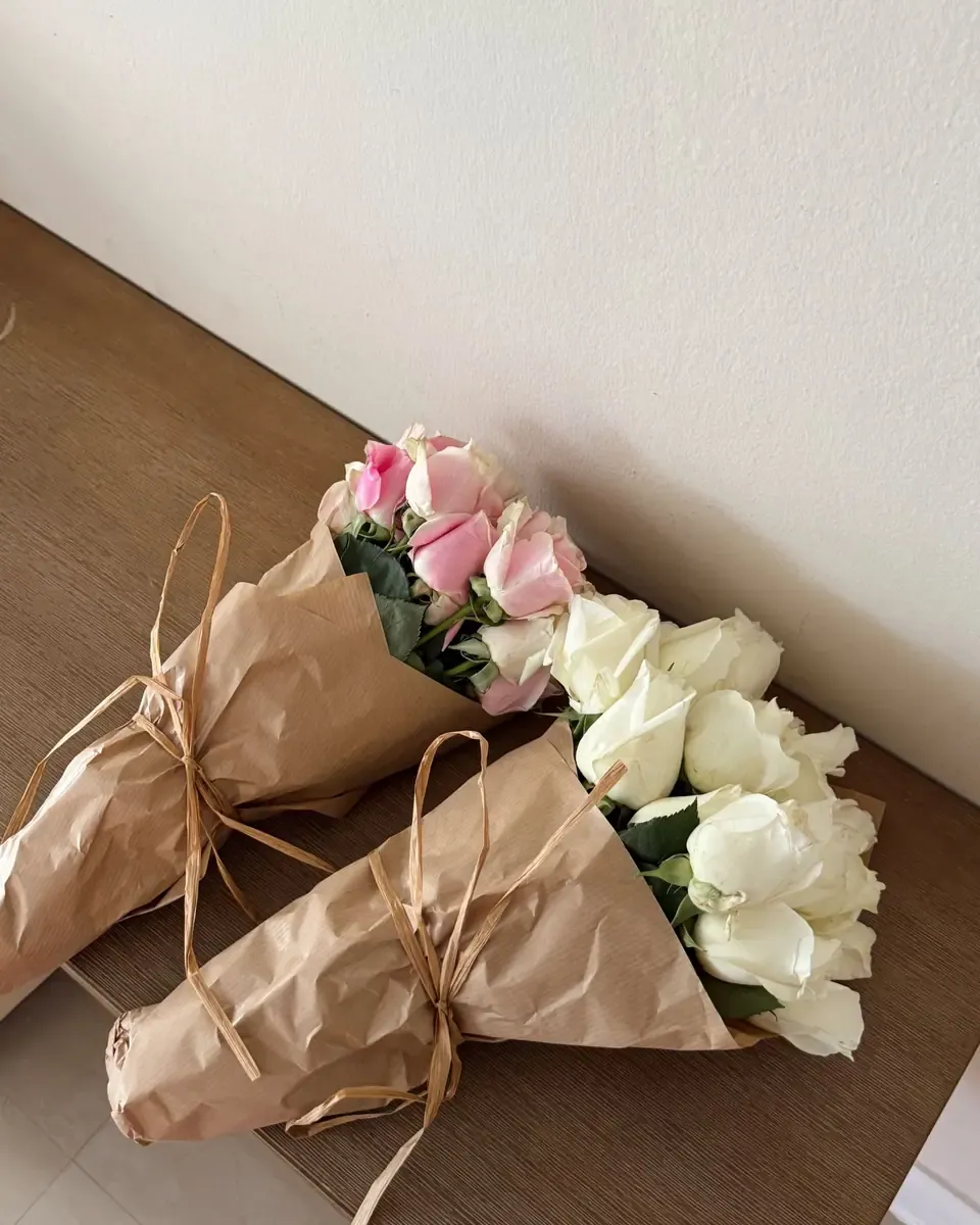 Hai bó hồng nhỏ gói giấy kraft đặt trên bàn gỗ