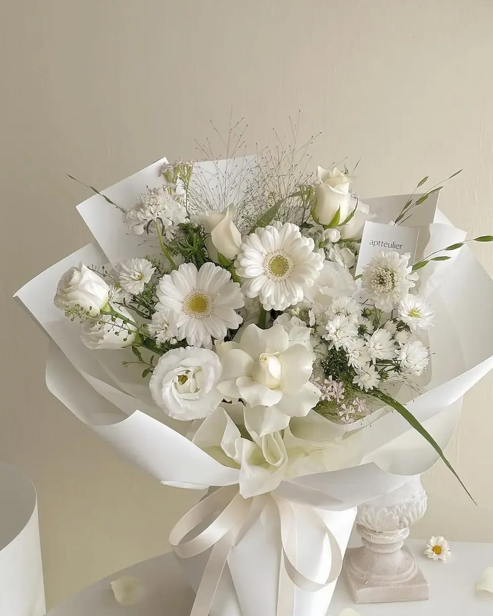 Bó cúc đồng tiền trắng và hoa trắng gói giấy trắng, buộc ruy băng cùng màu