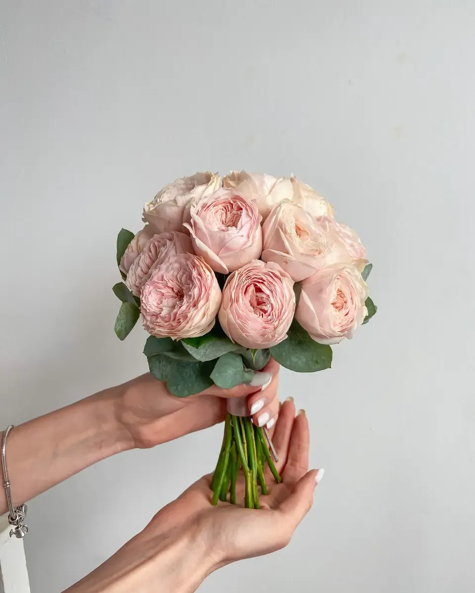 Bó tròn hoa hồng hồng phấn, hoa cam nhạt, hoa baby và lá bạch đàn, tay cầm ruy băng hồng
