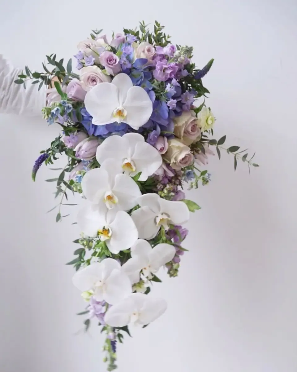 Bó thác nước hoa lan trắng, hoa hồng nhạt và calla, cô dâu váy ôm cầm trước người