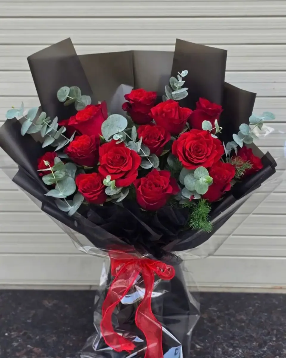 Hồng đỏ cùng lá bạch đàn gói giấy đen trong suốt, buộc ruy băng đỏ