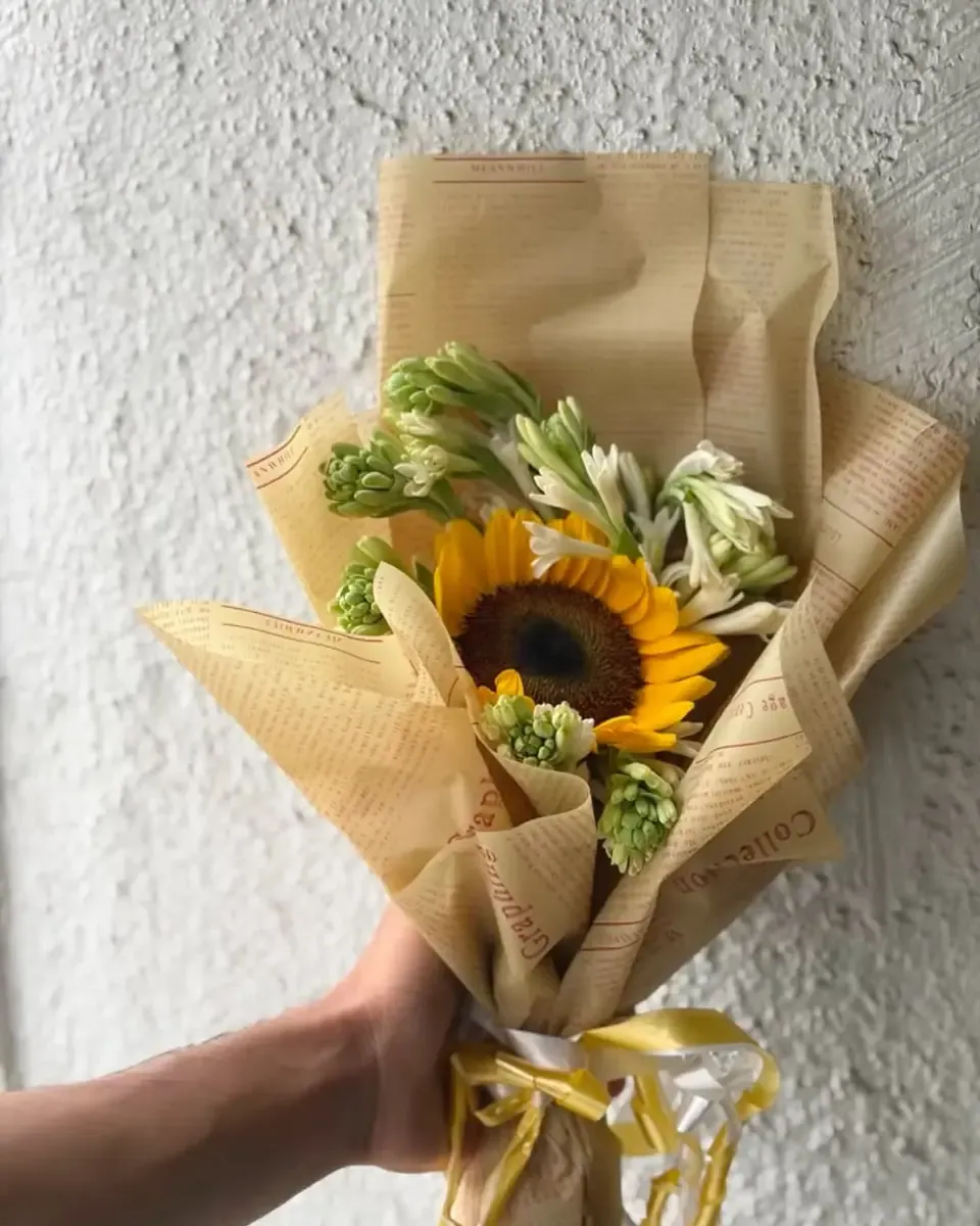 Một bông hướng dương lớn gói giấy kraft, được cầm trên tay