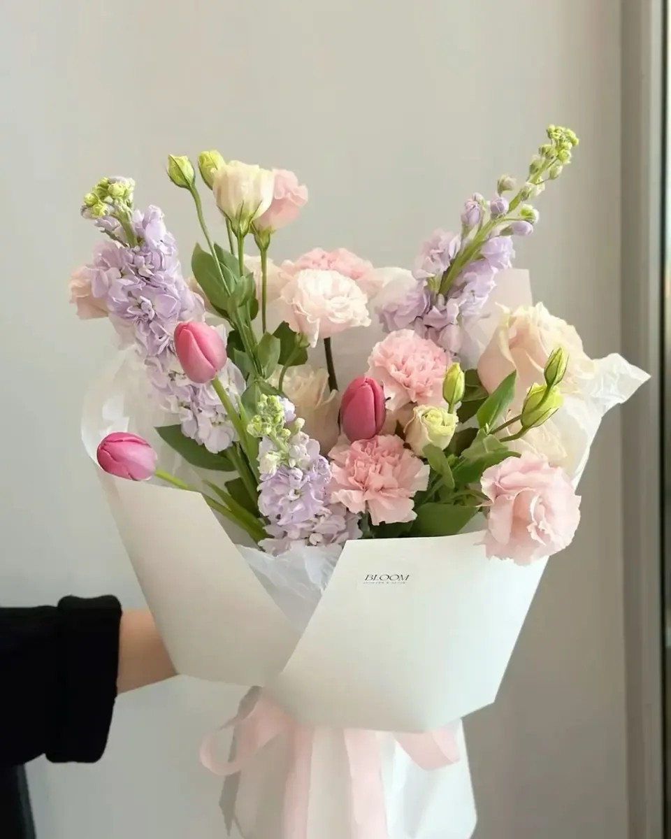 Bó tulip hồng, lisianthus tím nhạt gói giấy trắng buộc ruy băng trắng