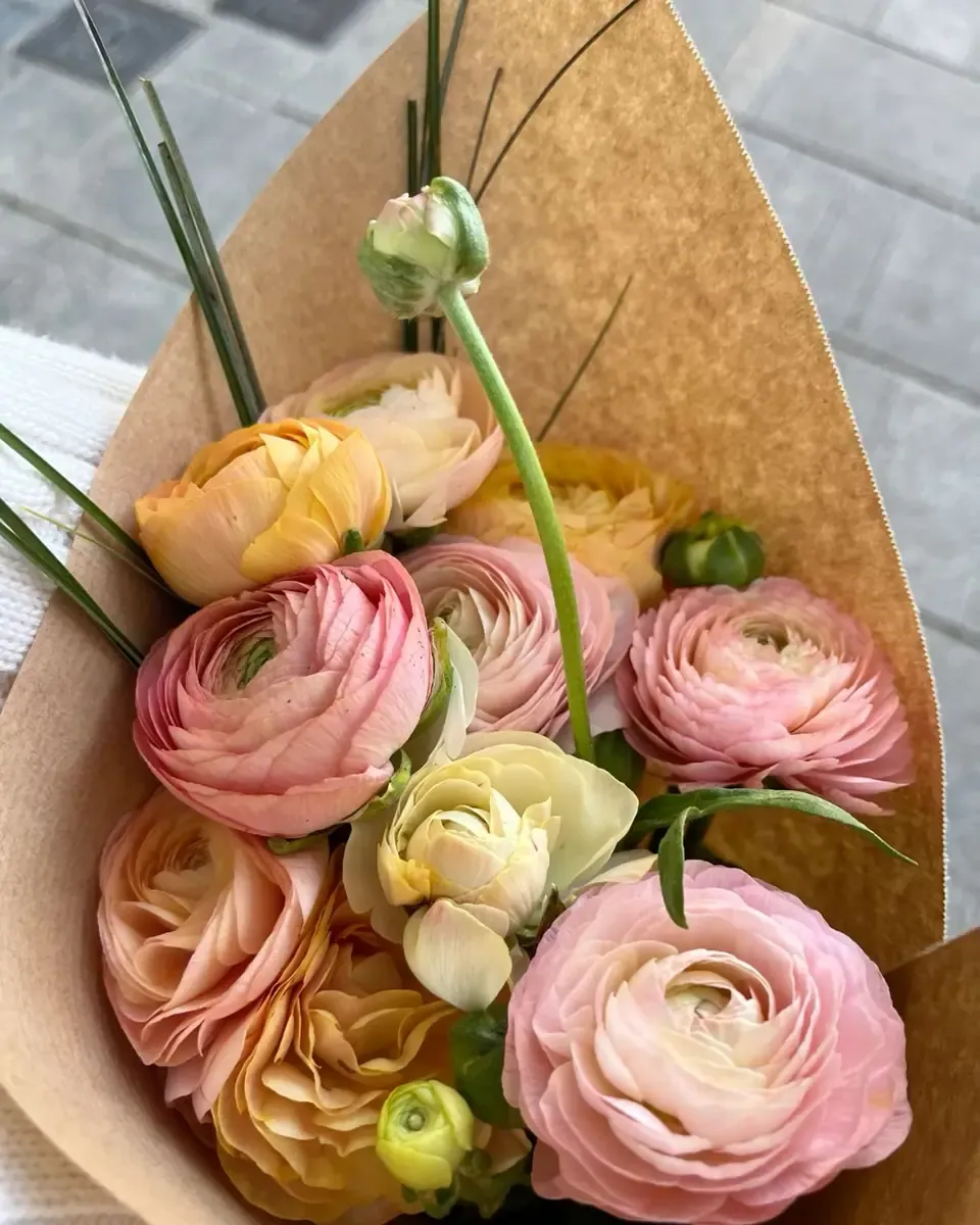 Bó mao lương hồng, vàng và cam gói giấy kraft, thân xanh dài, đặt trên nền sáng