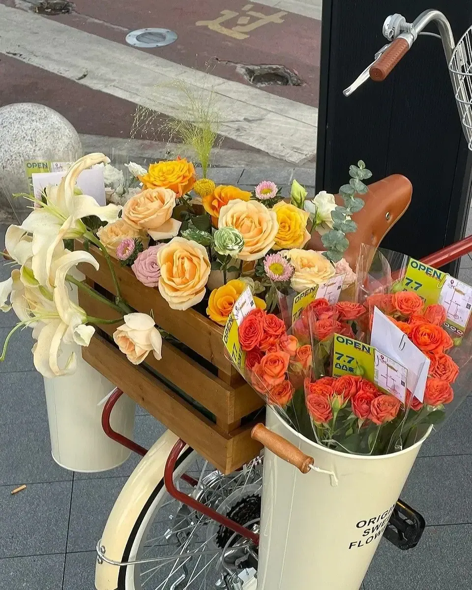 Xe đạp đỏ có xô trắng cắm bó hoa hồng hồng gói giấy trong đặt bên vỉa hè