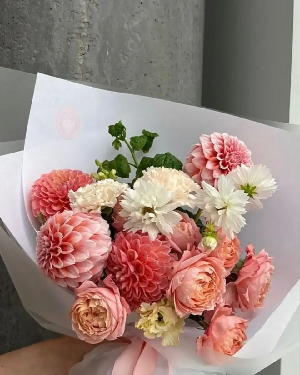 Bó thược dược hồng san hô cùng hồng nhạt và lá xanh, gói giấy trắng ruy băng hồng