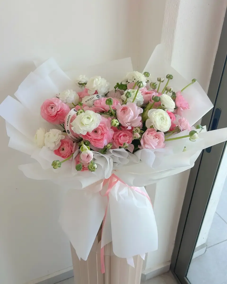 Bó mao lương hồng nhạt cùng cành lá xanh nằm trên bàn phủ vải