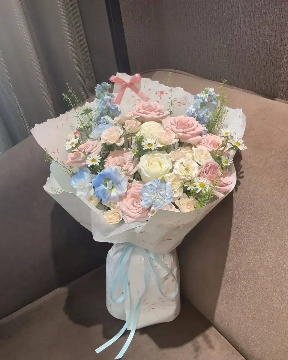 Bó hoa hồng hồng và hoa xanh dương pastel gói giấy trắng buộc ruy băng xanh nhạt