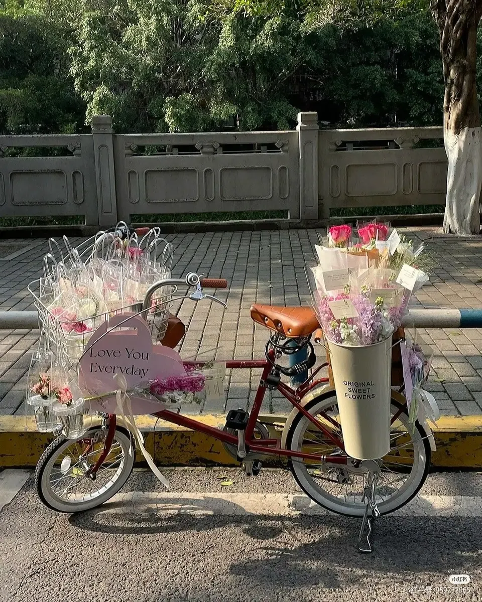 Xe đạp có giỏ gỗ chất đầy hoa hồng cam, hoa ly và hoa nhiều màu gói giấy ngoài trời