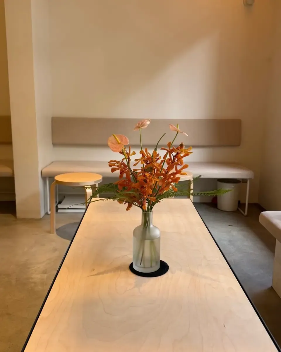 Bình nhỏ cắm hoa cam đặt trên bàn dài trong quán sáng