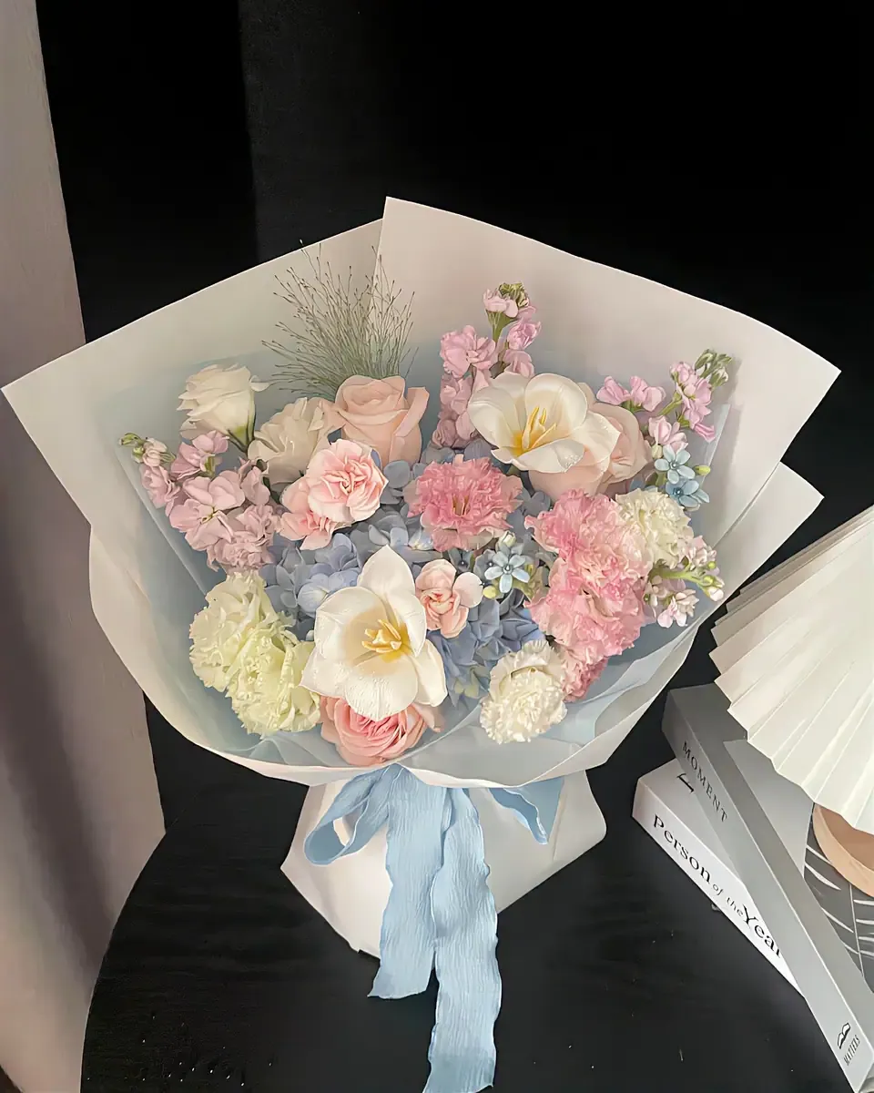 Bó hoa pastel hồng xanh trắng gói giấy trong buộc ruy băng xanh