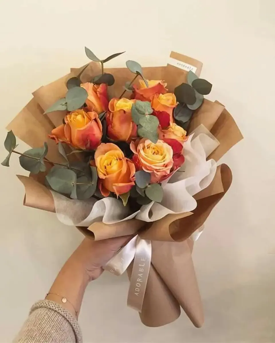 Bó hồng cam vàng gói giấy kraft và giấy trắng cùng lá bạch đàn