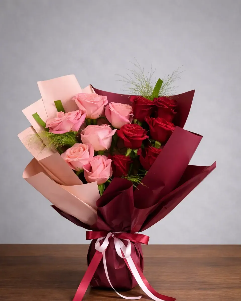 Bó hồng hồng và đỏ gói giấy đỏ đô, ruy băng hồng, đặt trên bàn gỗ