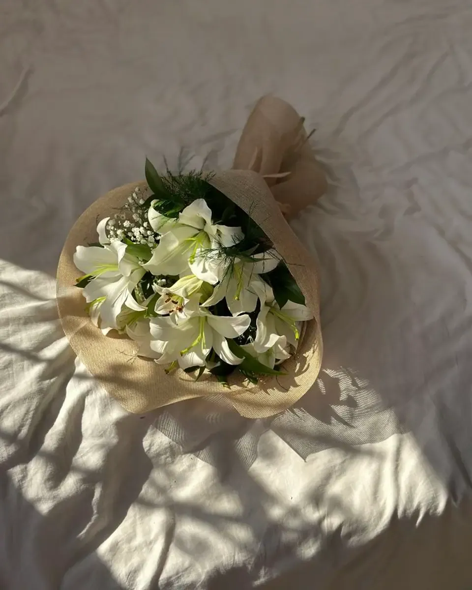 Bó ly trắng nhỏ gói giấy kraft đặt trên ga giường sáng