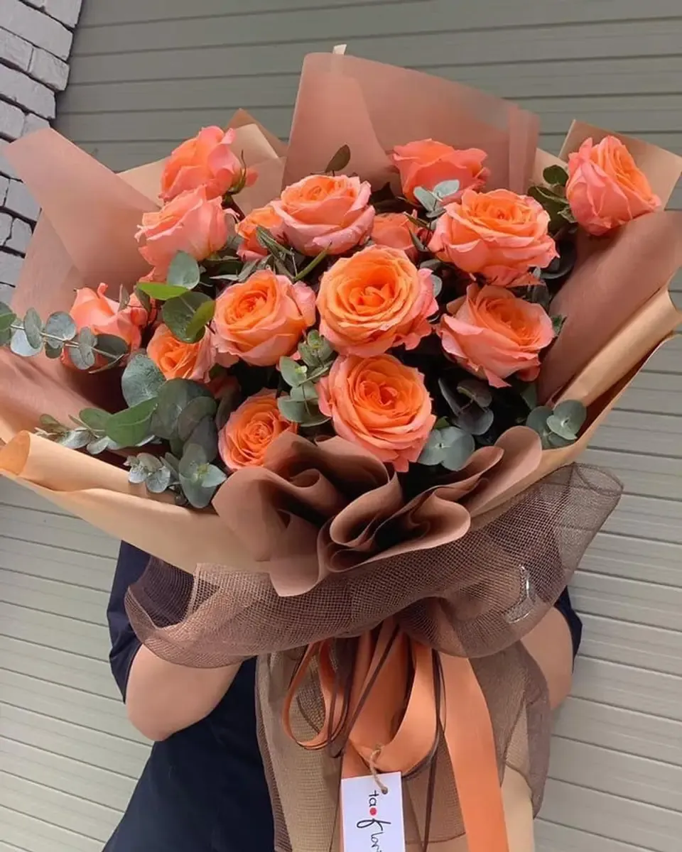 Bó hồng cam đào cùng lá bạch đàn gói giấy nâu cam