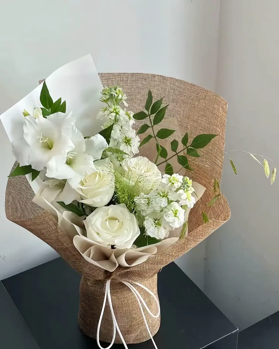 Bó hoa trắng gồm hồng và nhiều loại hoa nhỏ, gói giấy bao tải màu kem