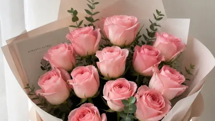 Bó hồng phấn gói giấy hồng và trắng, ruy băng hồng buộc gọn cạnh khung cửa sổ