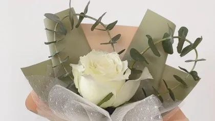 Bó hoa hồng trắng gói giấy xanh olive và cam đào, buộc ruy băng ren, kèm thẻ nhỏ