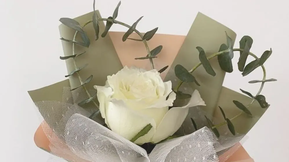 Bó hoa hồng trắng gói giấy xanh olive và cam đào, buộc ruy băng ren, kèm thẻ nhỏ