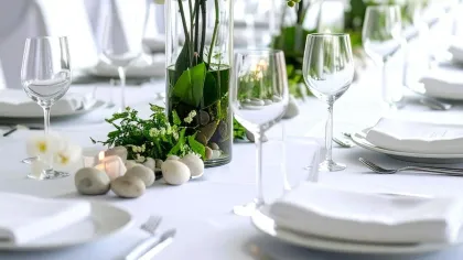 Lan hồ điệp trắng cắm trong bình thủy tinh cao đặt giữa bàn tiệc dài dưới ánh sáng ban ngày
