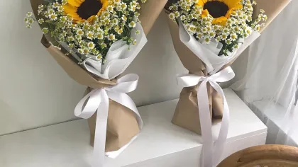 Hai bó nhỏ hướng dương và cúc họa mi gói giấy kraft, buộc ruy băng trắng