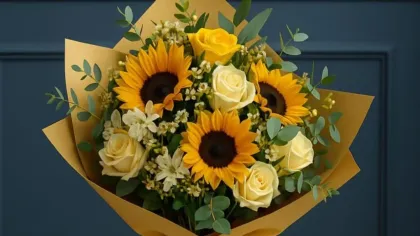 Bó hướng dương và hồng vàng gói giấy vàng, buộc ruy băng trắng đặt trên bàn nhỏ trước tường xanh
