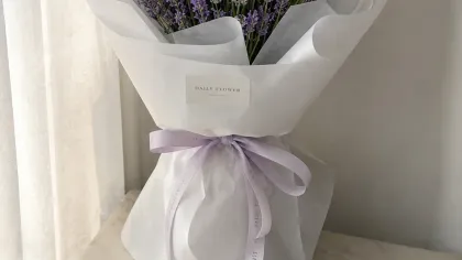 Bó oải hương tím gói giấy trắng, buộc ruy băng tím nhạt, đặt cạnh rèm cửa sáng