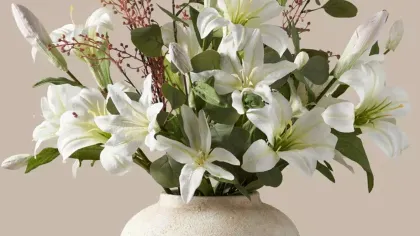 Bình gốm kem cắm hoa ly trắng, lá bạch đàn và cành hoa nhỏ trên nền be ấm