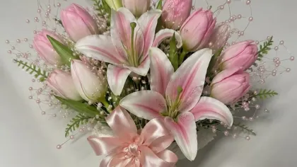 Bó hoa ly và tulip hồng buộc nơ ruy băng hồng phấn, cuống quấn lụa hồng trên nền xám