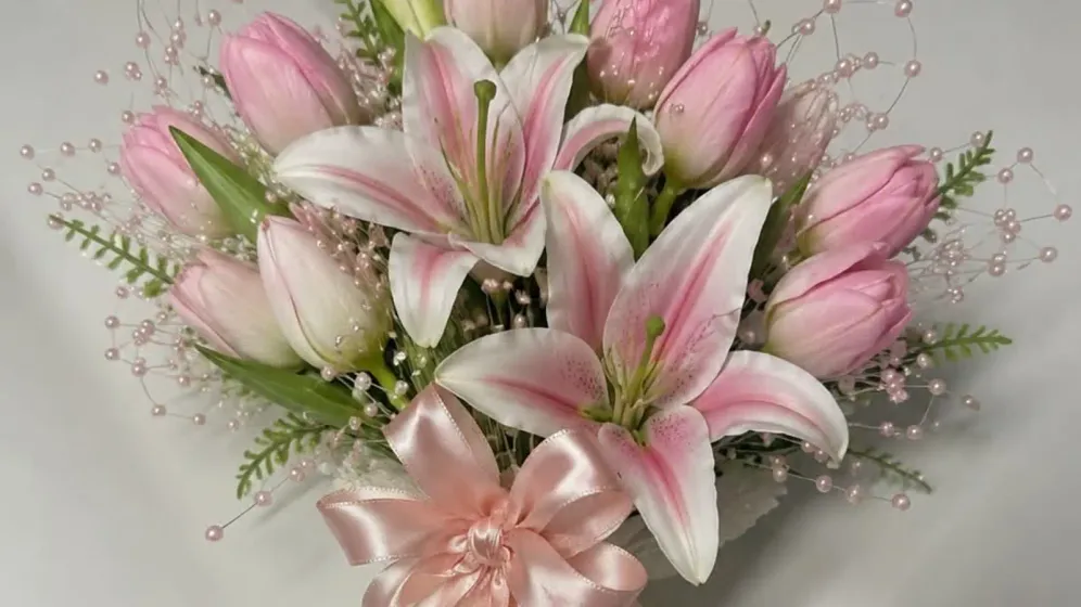 Bó hoa ly và tulip hồng buộc nơ ruy băng hồng phấn, cuống quấn lụa hồng trên nền xám
