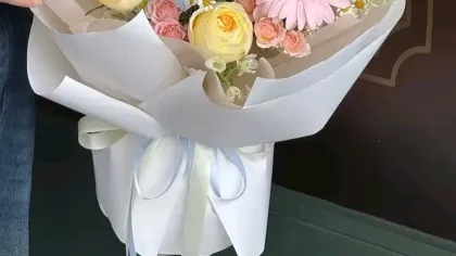 Bó hoa pastel phối hồng, vàng nhạt và xanh nhạt gói giấy trắng, ruy băng xanh
