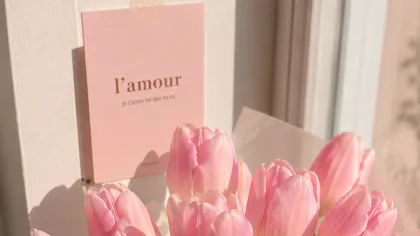 Bó tulip hồng gói giấy trắng kem đặt bên cửa sổ, nền sáng dịu