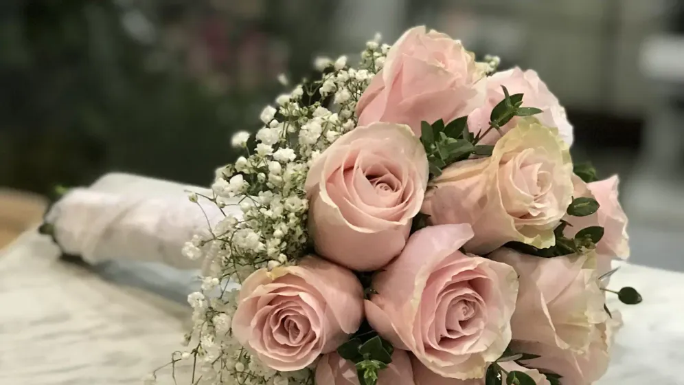 Bó hoa hồng phấn và hoa baby dáng tròn đặt trên mặt bàn đá cẩm thạch sáng