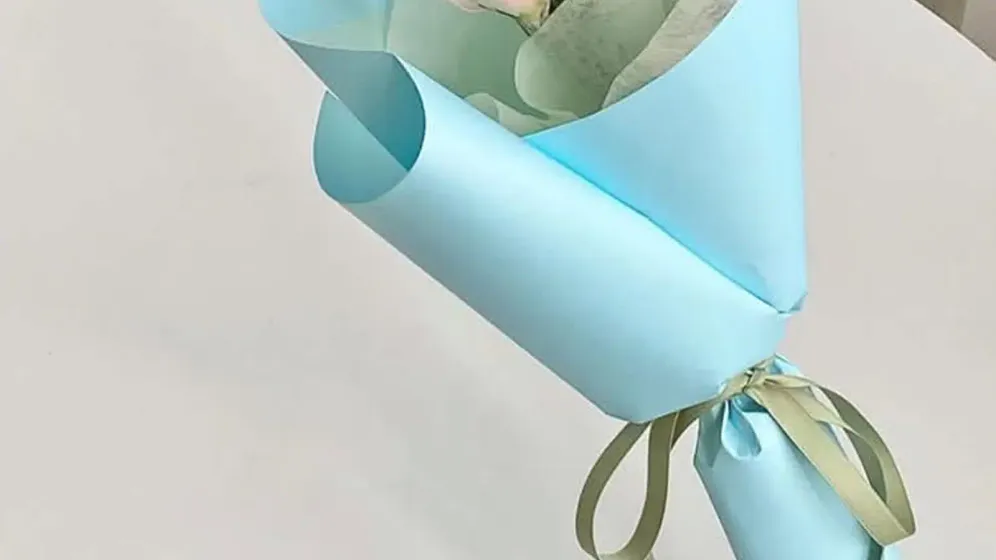 Vài bông hồng phấn cùng lá bạch đàn gói trong giấy xanh dương nhạt, buộc ruy băng vàng