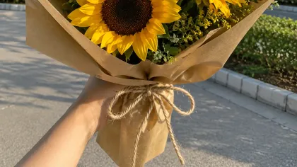 Bó hướng dương gói giấy kraft, buộc dây thừng, cầm ngoài trời nắng