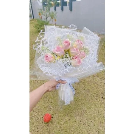 Bó hoa hồng phấn trong giấy gói trắng cầm tay